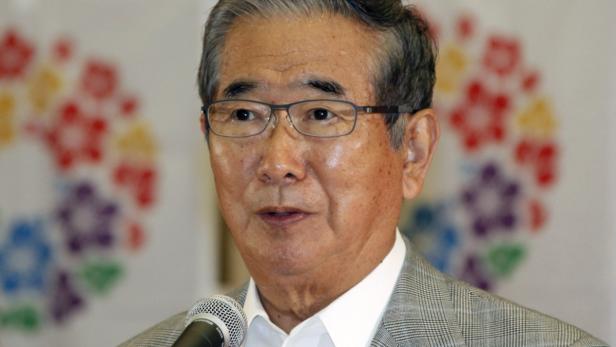 Ein älterer asiatischer Mann mit Brille spricht in ein Mikrofon.