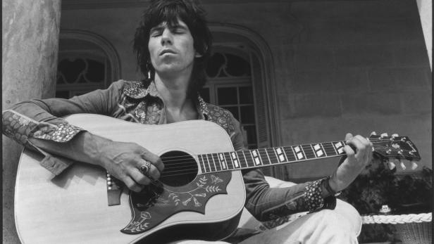 Keith Richards spielt Gitarre vor einem Gebäude.