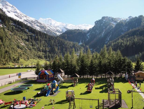 Ein Spielplatz in den Bergen mit Trampolinen, Rutschen und anderen Spielgeräten.
