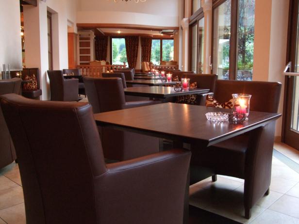 Ein Speisesaal mit braunen Ledersesseln und Tischen, die mit Kerzen dekoriert sind.