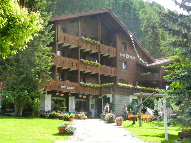 Das „Haus Senger“ mit Restaurant und blumengeschmückten Balkonen in einer grünen Umgebung.