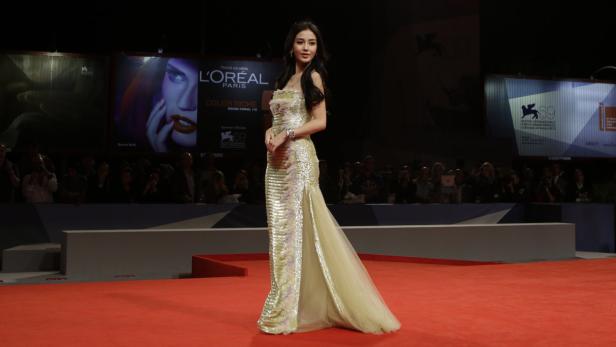 Eine Frau in einem goldenen Kleid auf dem roten Teppich der Filmfestspiele von Venedig.