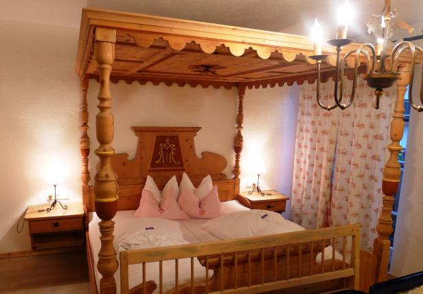 Ein Himmelbett aus Holz mit Nachttischen und Lampen in einem Schlafzimmer.