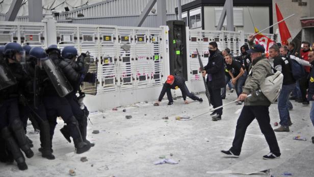 Bei einer Demonstration stehen sich Polizisten in Schutzkleidung und Demonstranten gegenüber.
