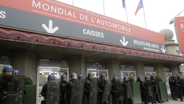Polizisten in Schutzausrüstung stehen vor dem Eingang des „Mondial de l'Automobile“ in Paris.