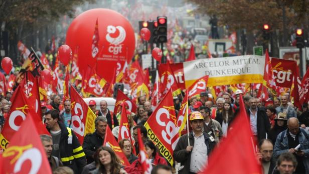 Eine Demonstration mit roten Fahnen und Ballons der CGT und einem Banner von Arcelor Mittal in Dunkerque.