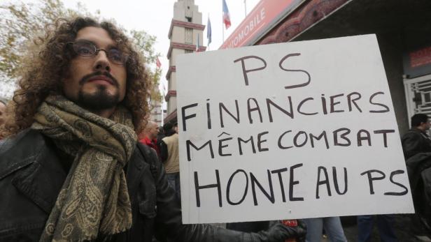 Ein Demonstrant hält ein Schild mit der Aufschrift „PS Financiers Même Combat Honte au PS“.