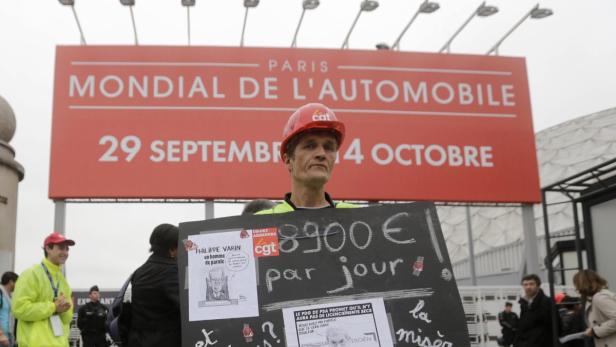 Ein Mann demonstriert mit einem Schild vor dem „Mondial de l'Automobile“ in Paris.