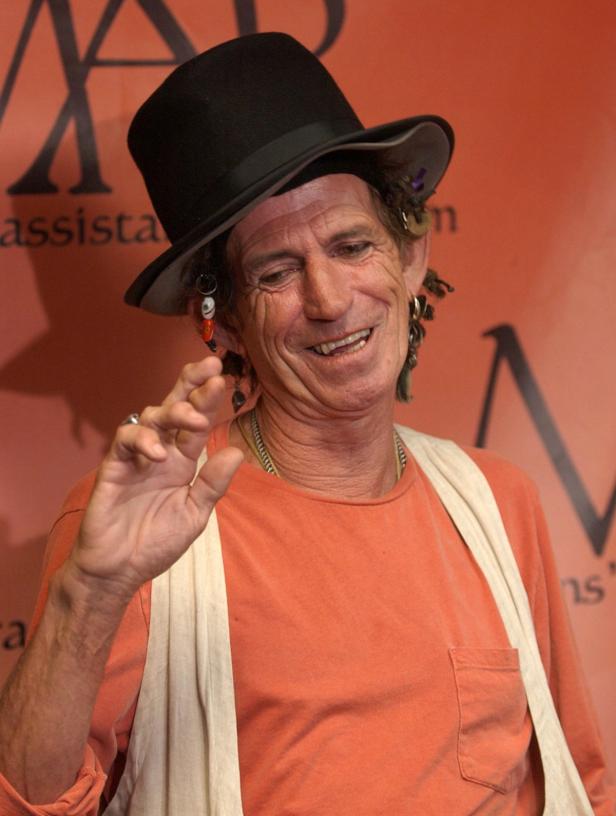 Keith Richards mit Hut und Ohrringen lächelt.
