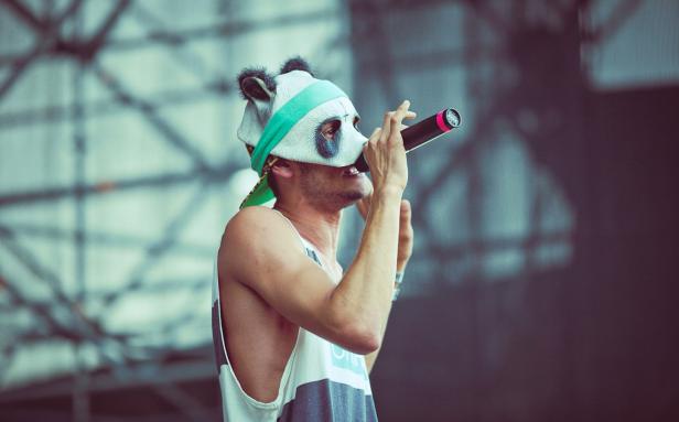 Ein Mann mit Panda-Maske singt in ein Mikrofon.
