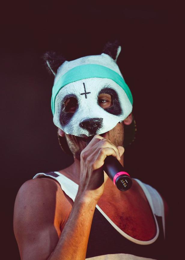 Ein Mann mit Panda-Maske singt in ein Mikrofon.