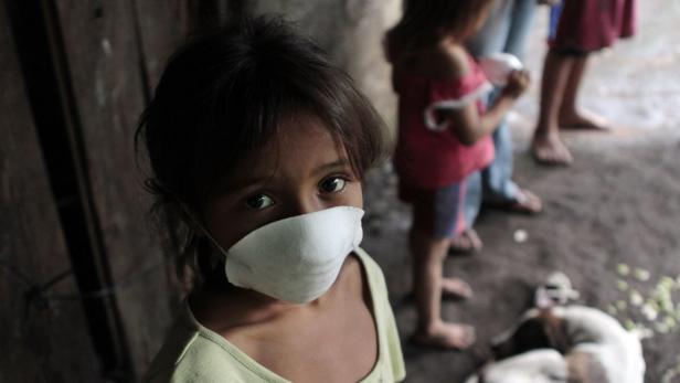 Ein junges Mädchen trägt eine Gesichtsmaske und blickt in die Kamera.