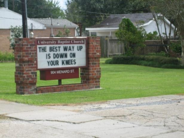Ein Schild der University Baptist Church zitiert: „The best way up is down on your knees“.