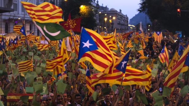 Eine Menschenmenge demonstriert mit katalanischen Flaggen in einer Stadt.