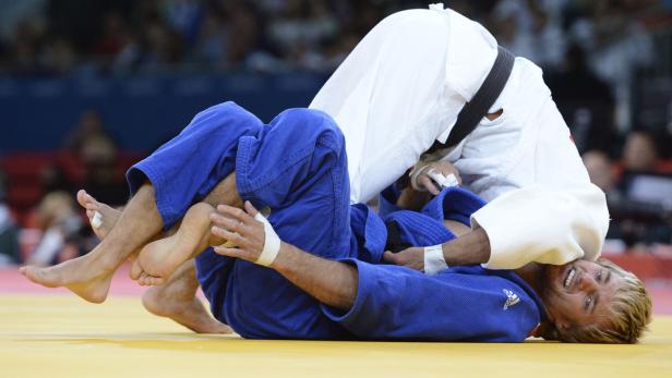 Zwei Judoka kämpfen auf einer gelben Matte.
