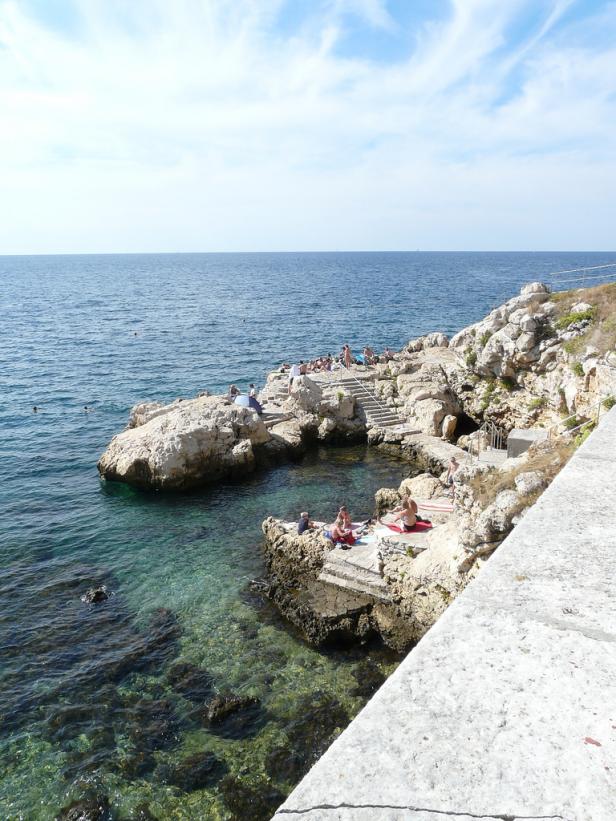 Menschen entspannen sich an einem sonnigen Tag auf den Felsen am Meer.