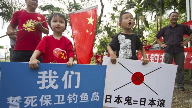 Kinder demonstrieren mit chinesischen Flaggen und Schildern gegen Japan.