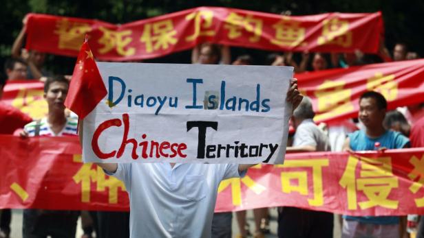 Menschen demonstrieren mit Schildern und chinesischen Flaggen für die Zugehörigkeit der Diaoyu-Inseln zu China.
