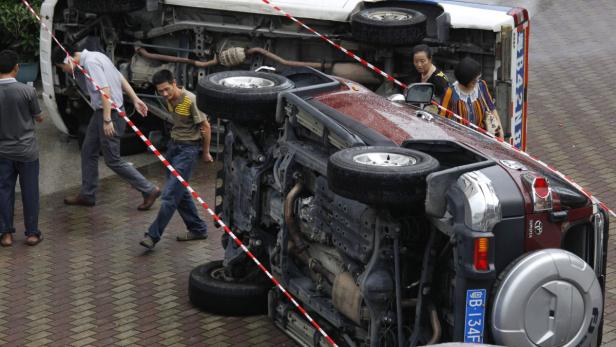 Ein auf dem Dach liegender Toyota Geländewagen, umgeben von Absperrband und mehreren Personen.