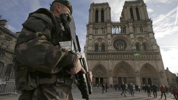 Ein Soldat mit Gewehr steht vor der Kathedrale Notre-Dame in Paris.