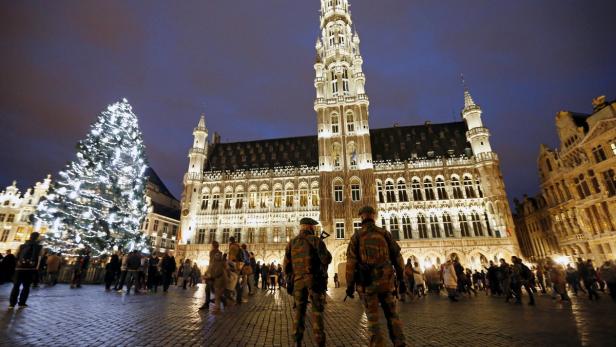 Der Grand Place in Brüssel mit Weihnachtsbaum und Menschenmenge, bewacht von Soldaten.
