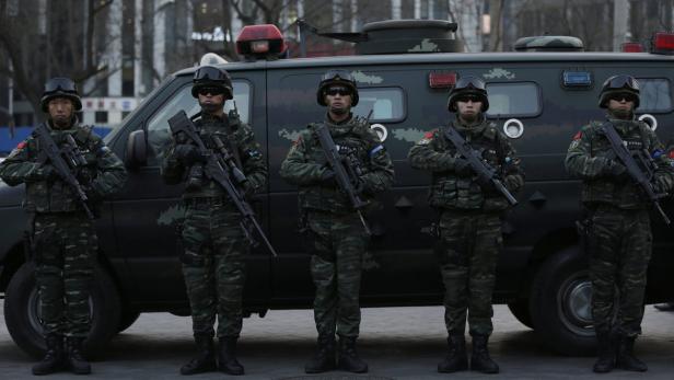 Fünf chinesische Soldaten stehen in Tarnuniform vor einem Militärfahrzeug.