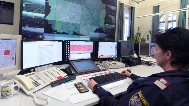 Eine Polizistin arbeitet in einer Überwachungszentrale mit mehreren Bildschirmen.