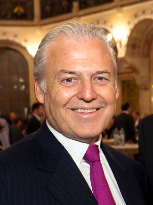 Ein lächelnder Mann im Anzug mit lila Krawatte.