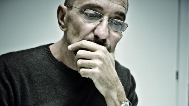 … Ein Mann mit Brille und Schnurrbart denkt nach, die Hand am Kinn.
