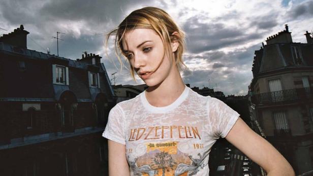 Eine junge Frau mit einem Led Zeppelin T-Shirt vor dem Hintergrund von Pariser Dächern.