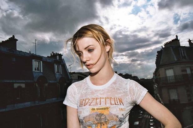 Eine junge Frau mit einem Led Zeppelin T-Shirt vor dem Hintergrund von Pariser Dächern.