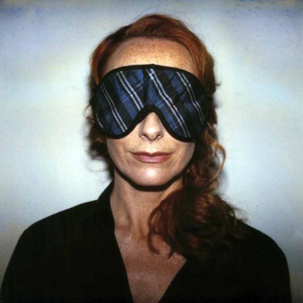 Eine Frau mit roten Haaren trägt eine Schlafmaske.