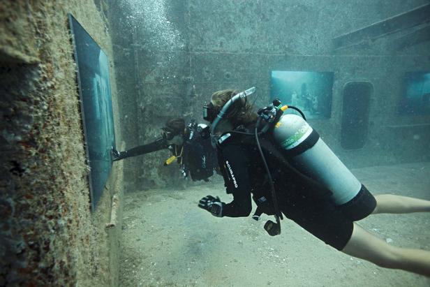 Zwei Taucher erkunden ein versunkenes Schiffswrack unter Wasser.