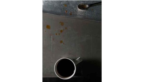 Eine Tasse Kaffee steht auf einer unordentlichen Metalloberfläche.