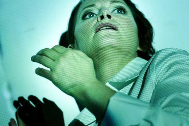 Eine Frau mit hellgrünem Gesichtsausdruck blickt nach oben.