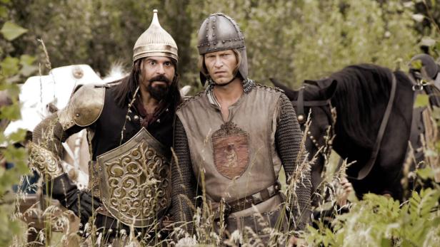Zwei Ritter in Rüstung stehen mit ihren Pferden in einem Feld.