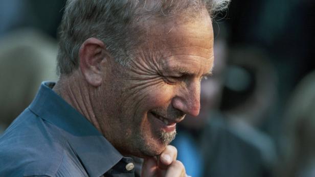 Ein lächelnder Kevin Costner mit der Hand am Kinn.