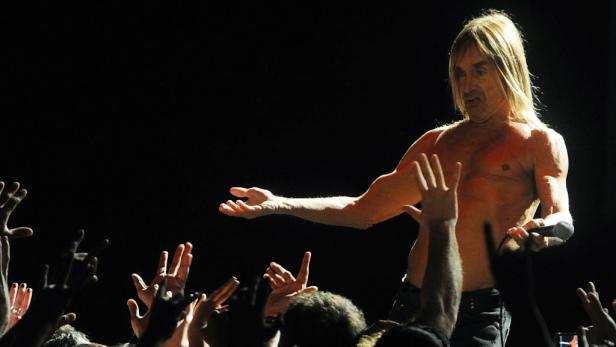 Iggy Pop steht mit nacktem Oberkörper vor einer jubelnden Menge auf der Bühne.