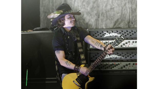 Johnny Depp spielt Gitarre auf einer Bühne.