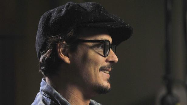 Ein Mann mit Brille und Schiebermütze im Profil.