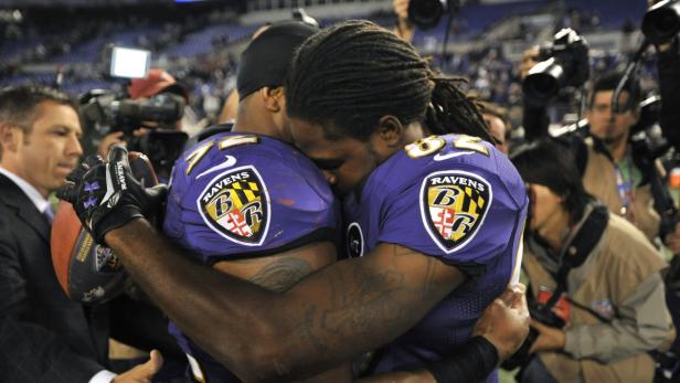 Zwei Footballspieler der Baltimore Ravens umarmen sich auf dem Spielfeld.