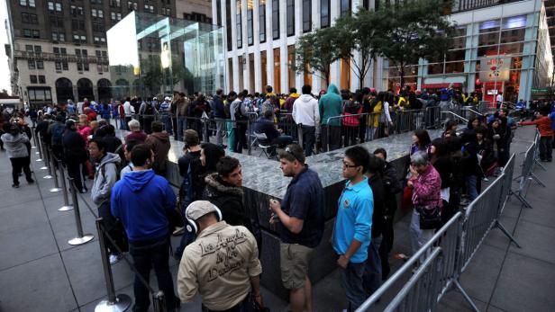 Eine lange Schlange von Menschen wartet vor einem Apple Store.