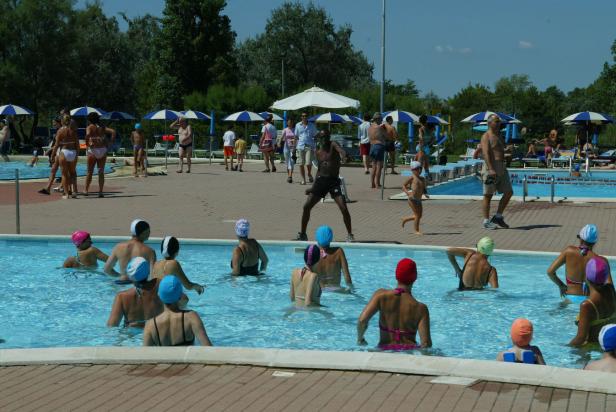 Eine Gruppe von Menschen nimmt an Wassergymnastik in einem Schwimmbad teil.