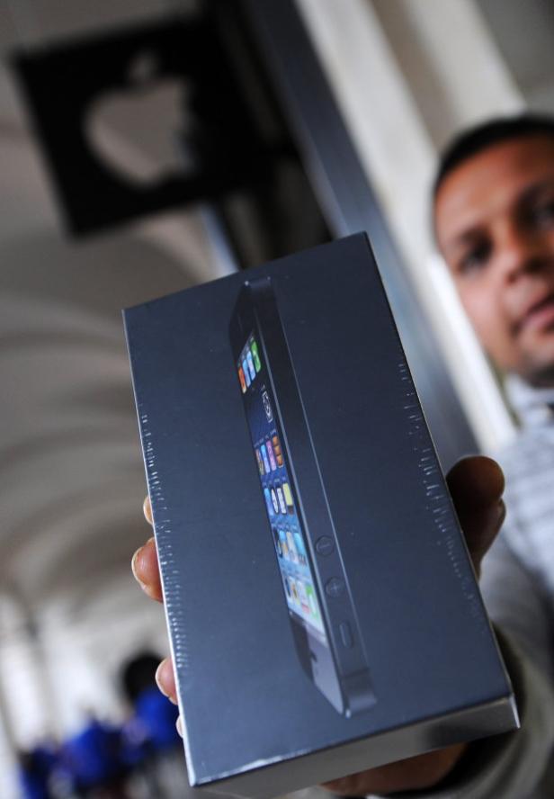 Ein Mann hält eine verpackte iPhone-Schachtel in einem Apple Store in die Höhe.