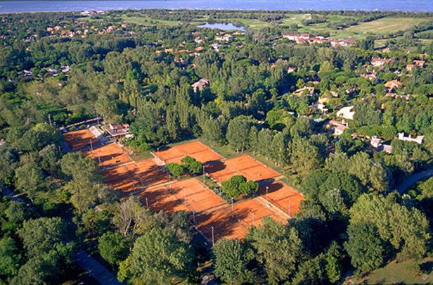 Luftaufnahme von mehreren Tennisplätzen, umgeben von Bäumen und Wohnhäusern.