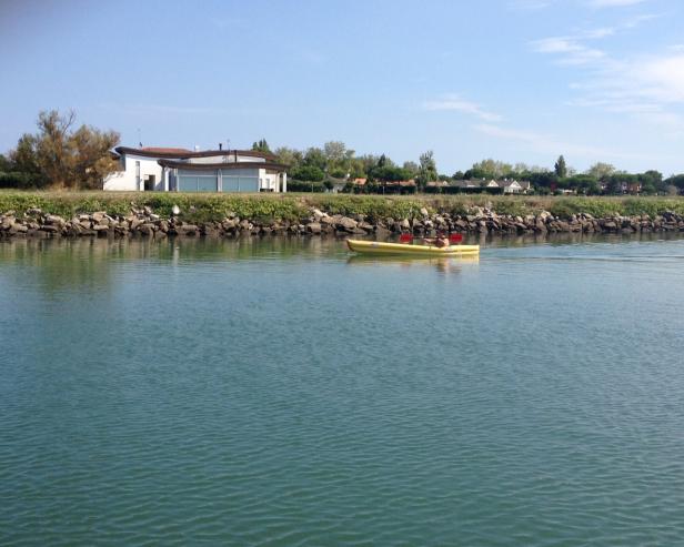 Eine Person fährt mit einem gelben Kajak auf einem ruhigen Gewässer.