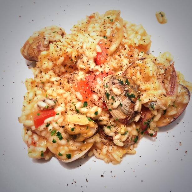 Ein Teller mit Risotto Frutti di Mare, garniert mit Petersilie und schwarzem Pfeffer.