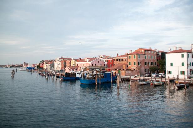 Bunte Häuser und Fischerboote säumen einen Kanal in Venedig.