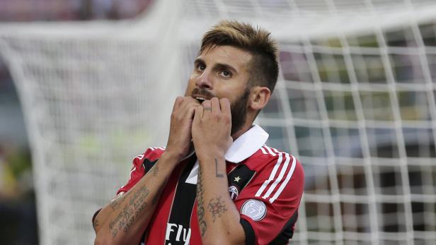 Ein Fußballspieler mit Tattoos beißt nervös auf seinen Fingernägeln.