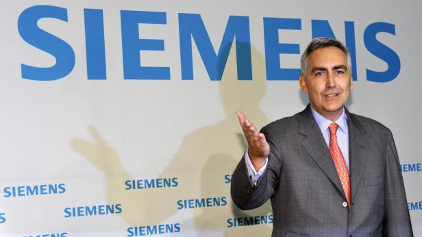 Ein Mann im Anzug steht vor einem Siemens-Logo.